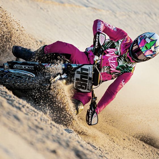 MX rider in pink MX gear riding in the sand